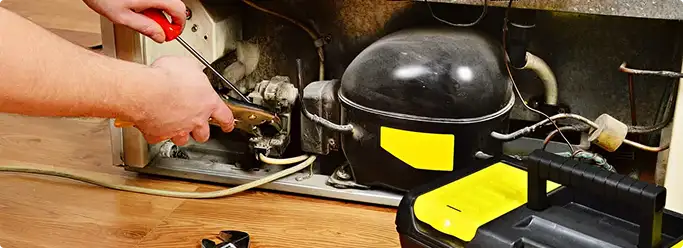 Refrigerator repair technician fixing the compressor and wiring in Charlestown, MA
