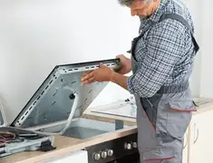 Appliance repair technician installing a built-in cooktop in Cambridge, MA