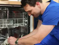 Dishwasher repair technician inspecting and servicing an open dishwasher in Cambridge, MA