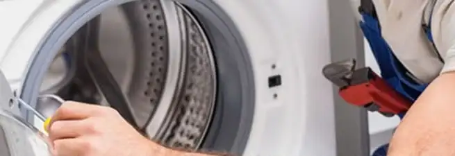 Appliance technician repairing a clothes dryer drum and internal parts in Cambridge, MA