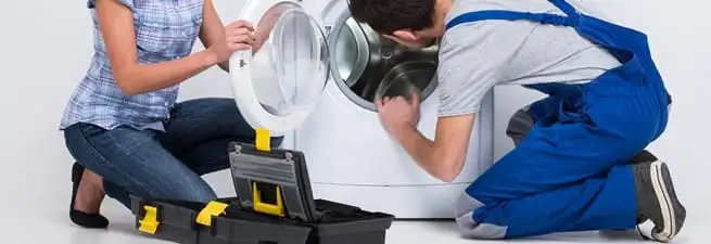 Washer repair technician inspecting a front-load washing machine with tools in Cambridge, MA