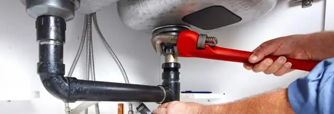 Garbage disposal repair technician tightening the sink drain and disposal connection in Cambridge, MA
