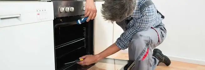 Oven repair technician inspecting and servicing an electric oven in Cambridge, MA