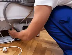 Appliance repair technician fixing refrigerator water line and connections in Cambridge, MA