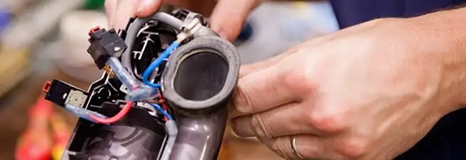 Vacuum repair technician reconnecting wiring and components in Cambridge, MA