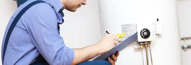 Water heater repair technician inspecting the unit and recording service notes in Cambridge, MA