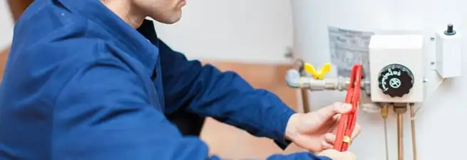 Water heater repair technician adjusting the temperature control and gas valve in Cambridge, MA